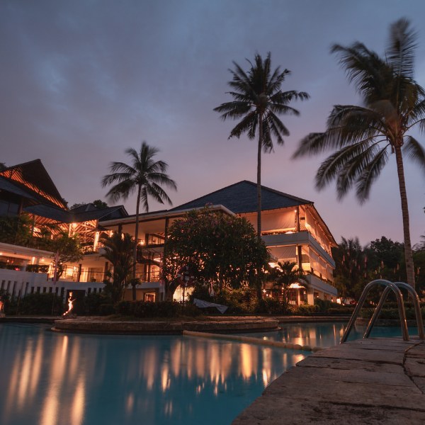 Tropical resort lit up at dusk beside a swimming pool, representing hotel visibility in AI travel search