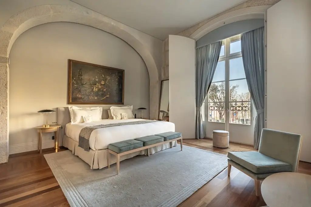 Bright boutique hotel guest room with an arched alcove, king bed, and tall windows, representing independent hotel digital presence